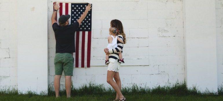 hombre que sostiene una bandera de los ee.uu. en la pared de una casa