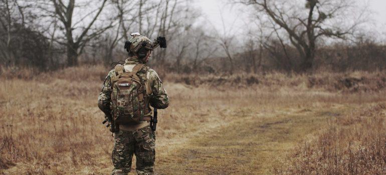 Hombre que llevaba un uniforme militar y caminar a través de bosques