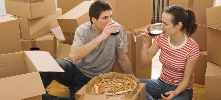 Couple having wine and pizza after transferring utilities after moving