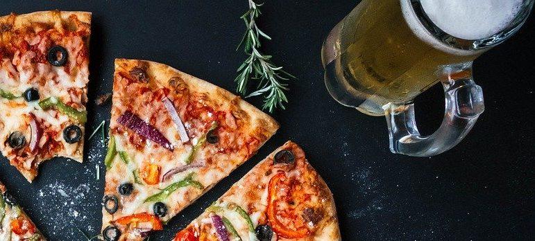 Sliced pizza and a pint of beer