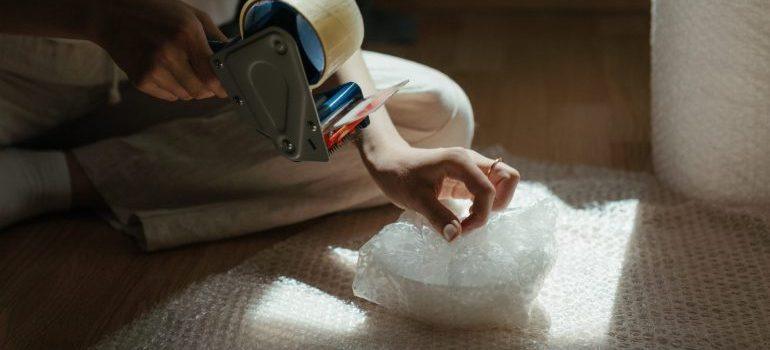 woman wrapping ceramics in bubble wrap