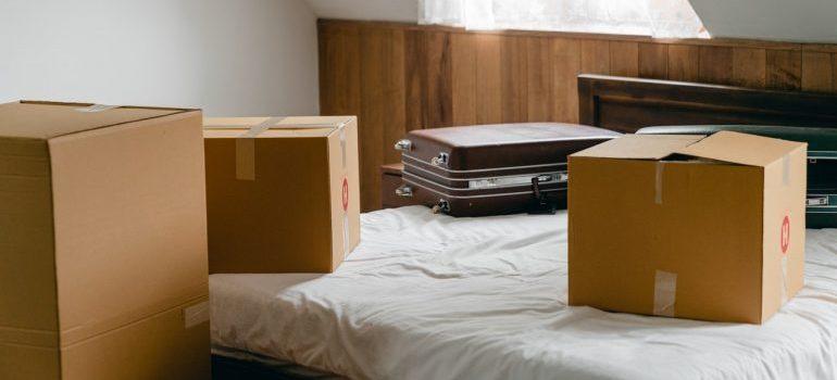 Cajas y una maleta en una cama que descomprimir antes de resolver después de mudarse a Houston.