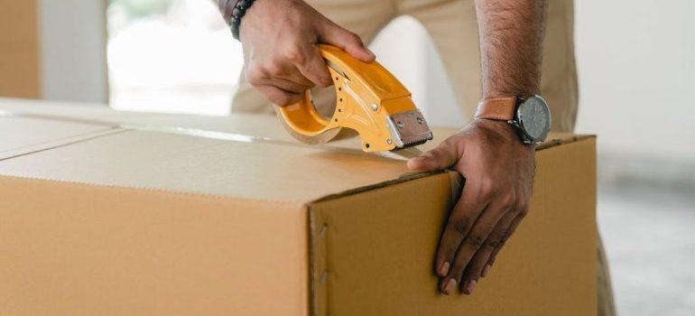 hombre pegando una caja de cartón