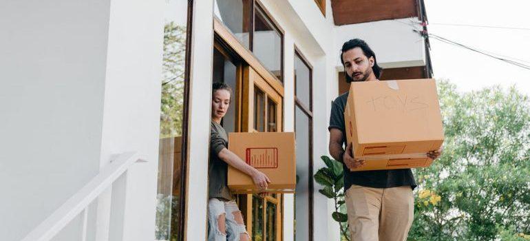 A man and a woman carrying cardboard boxes.