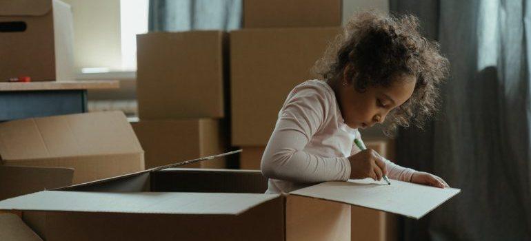 Una niña jugando en una caja de cartón.