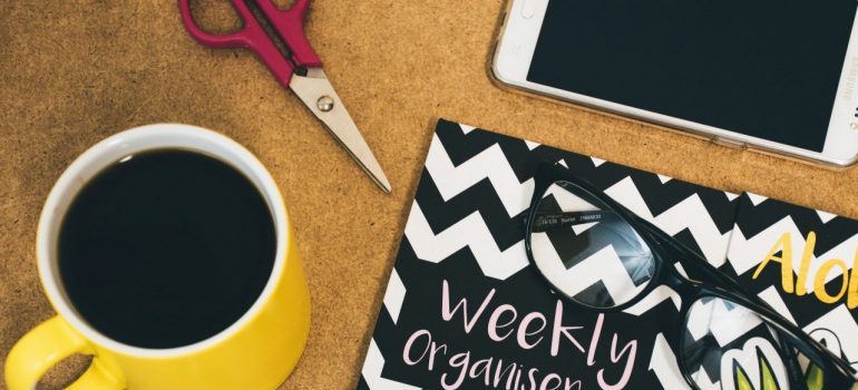 a cup and a weekly organizer on the table 