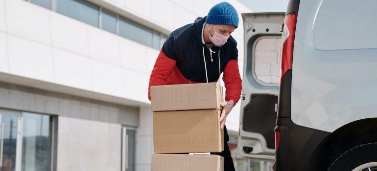 Man with a mask putting boxes in a truck