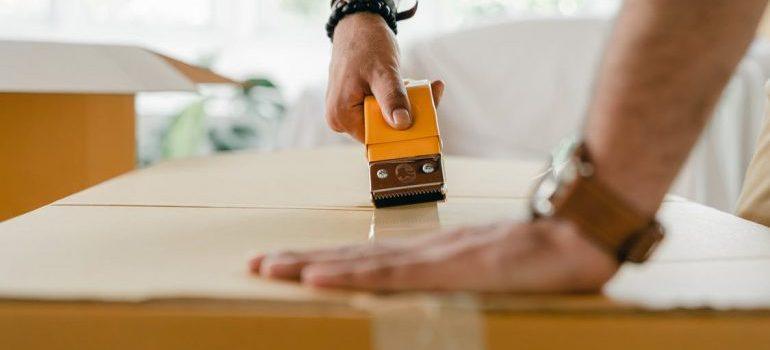 man taping a cardboard box