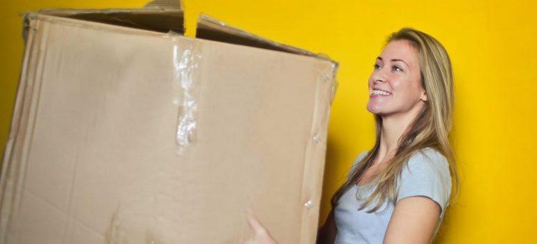 mujer cargando una caja de mudanza antes de mudarse de la Ciudad de Nueva York