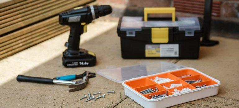 Drill and tools on the floor used to reassemble furniture after moving.
