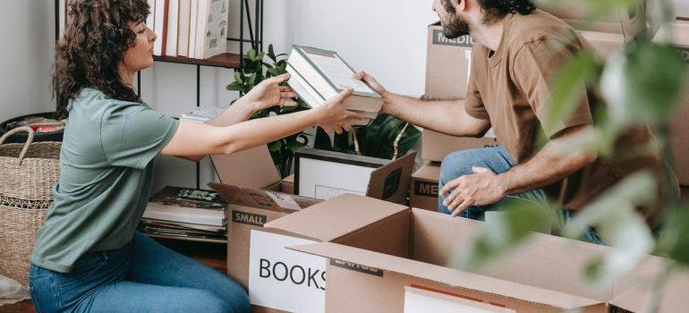 La mujer y los hombres empaque de libros en las cajas