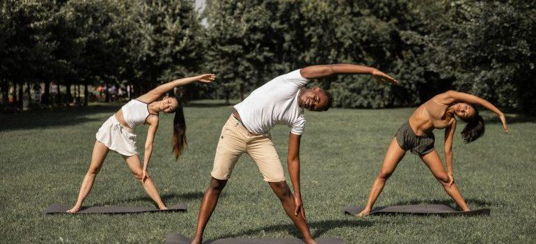 Three people doing yoga outside in the park