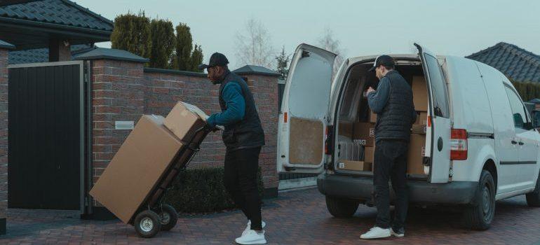 dos hombres de descarga del camión lleno de cajas, durante la primavera de mudanza de larga distancia