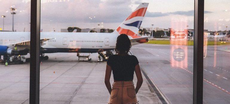 A girl in front of a window looking at a plane