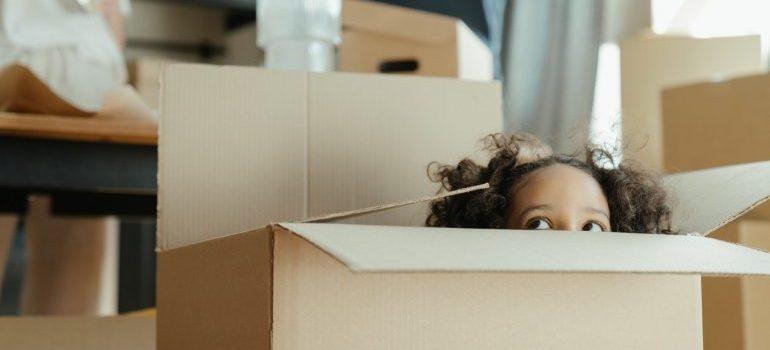 A little girl hiding inside a cardboard box