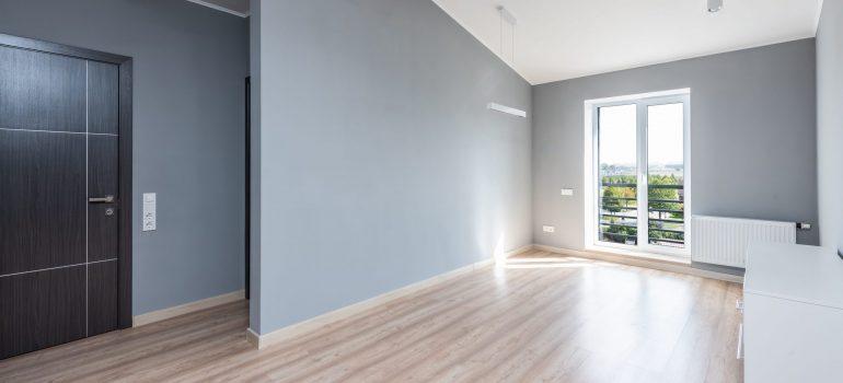 House interior of the empty house with grey walls, floor, side door and balcony glass door. 