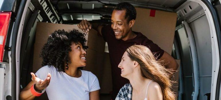 three people inside a van, smiling