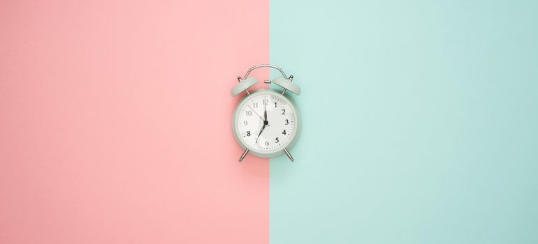 An alarm clock on a pink and blue surface.