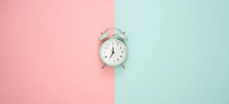 An alarm clock on a pink and blue surface