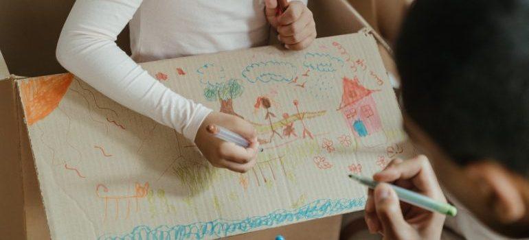 una madre y su hija tratar con los materiales de embalaje después de mudarse por el dibujo sobre el