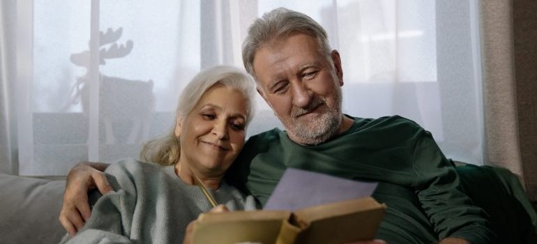 older man and a woman reading a book on the couch