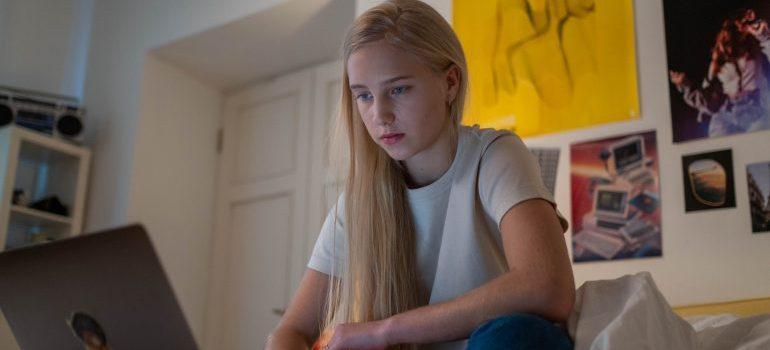 teenage girl browsing on laptop in her room