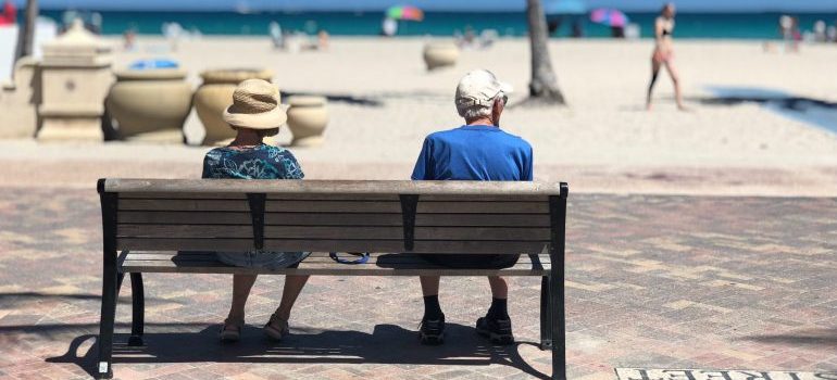 two retirees sitting on a bench near the beach