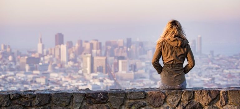 girl sitting on a rock platform viewing the city
