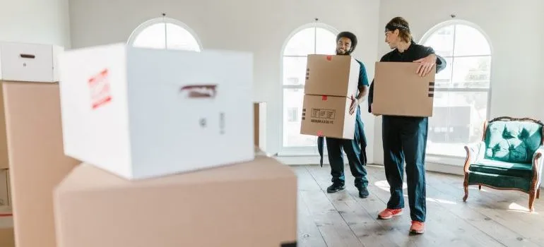 Two movers carrying moving boxes.