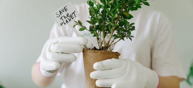 a woman holding a plant and sign save the planet