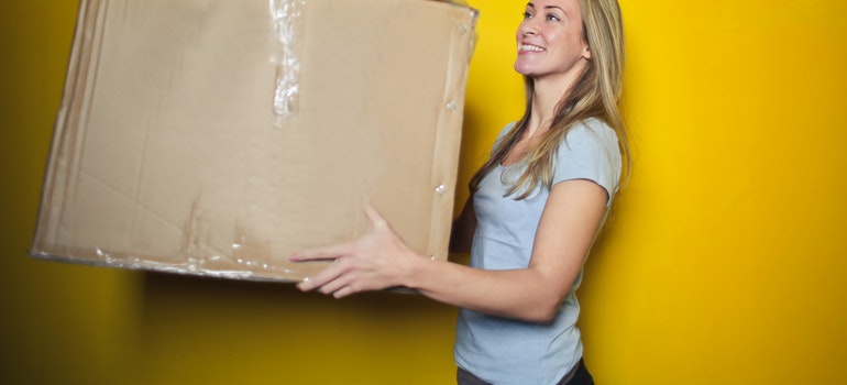 A woman packing after deciding to move after thinking about the pros and cons of moving across the country
