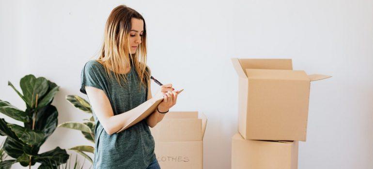 a woman making a list in front of cardboard boxes