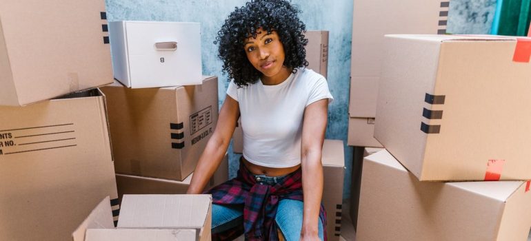 a woman sitting proudly in between packed cardboard boxes to represent the dedication for moving from Richmond to Alabama