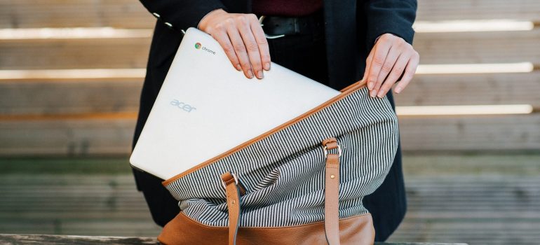 El día de la mudanza las necesidades de una mujer está poniendo Acer ordenador portátil en una bolsa. 