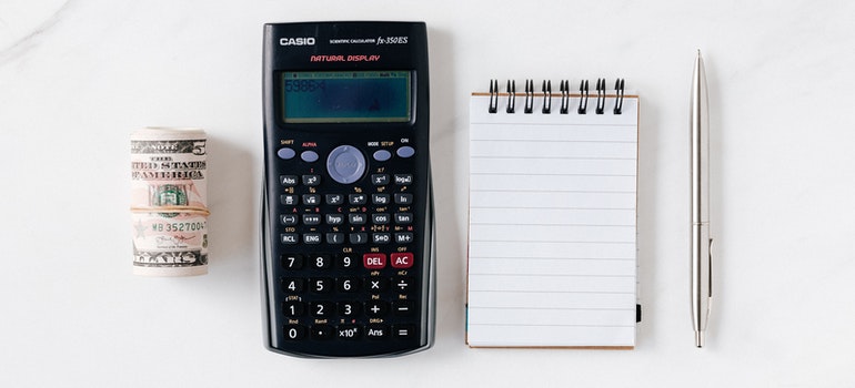 Money, calculator, notepad and a pen on a table