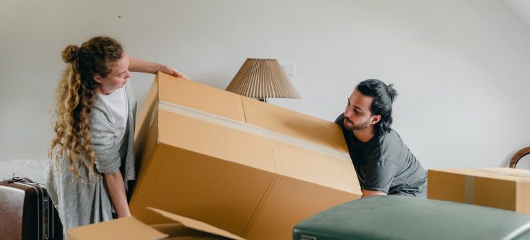 a couple handling a large box in their bedroom