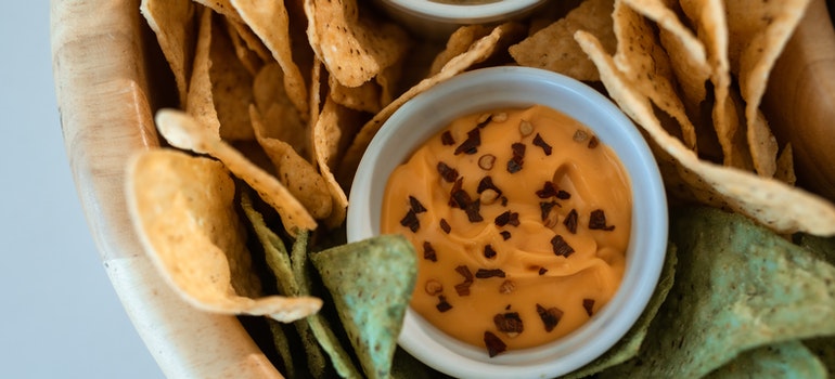 Snacks are in a bowl, with a cup filled with sauce in the middle.