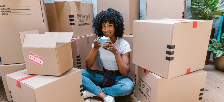 una chica sentada entre las cajas, antes de trasladarse desde Miami a Austin