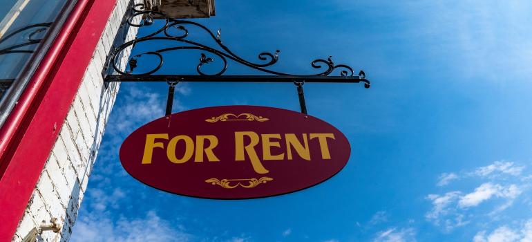 a sign that says "for rent" hanging from a building