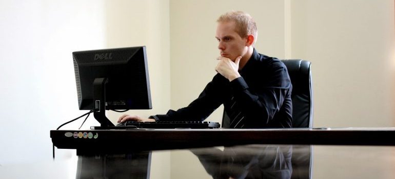 un hombre mirando a su ordenador, y pensando en mudarse de Dallas a NC