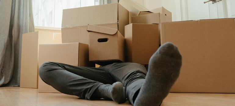 A man on the ground covered in moving boxes before his multi-day move