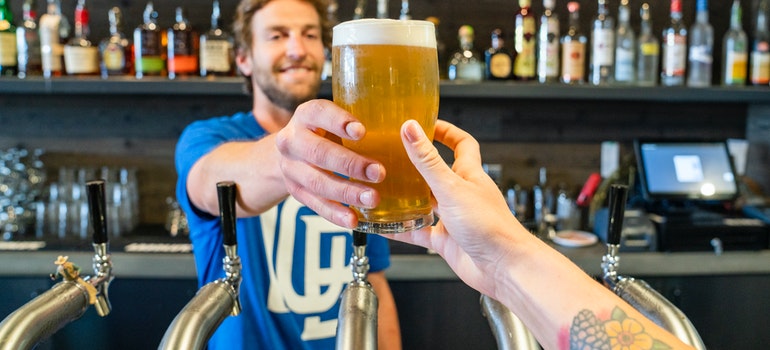 Man handing a person a glass of beer before moving from Houston to Boerne 