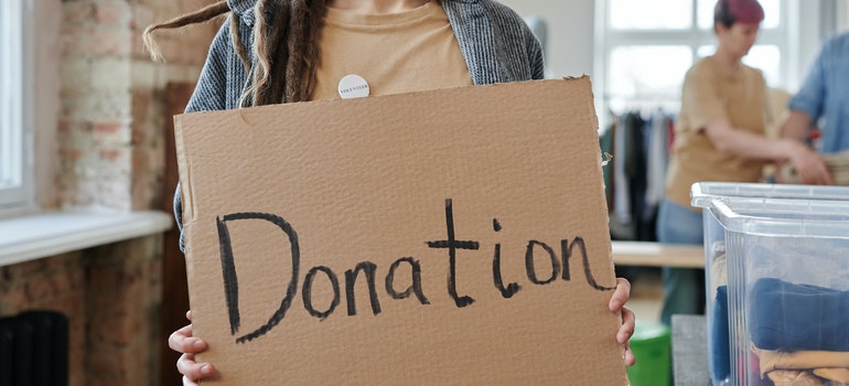 a woman holding a piece of cardboard that says donation