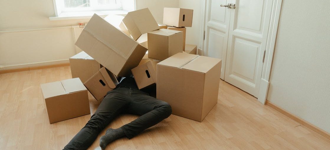 Un hombre cubierto por las cajas de pensar en maneras de reducir el estrés al mover su negocio a Maryland
