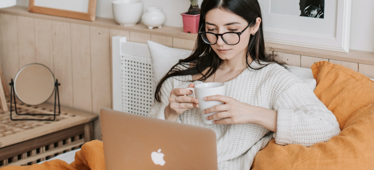 a girl drinking cofee and reading on lap top