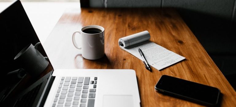 computer, pen, paper and a cup on the table 