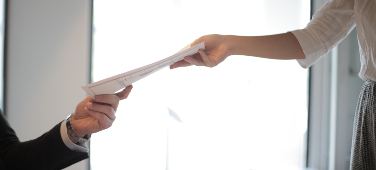 a person handing documents to another person 