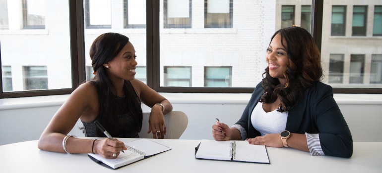 dos mujeres discutiendo acerca de encontrar un nuevo puesto de trabajo antes o después de mudarse a la Liga de la Ciudad