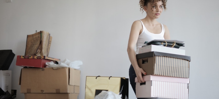 una mujer cargando cajas de cartón fuera de la habitación