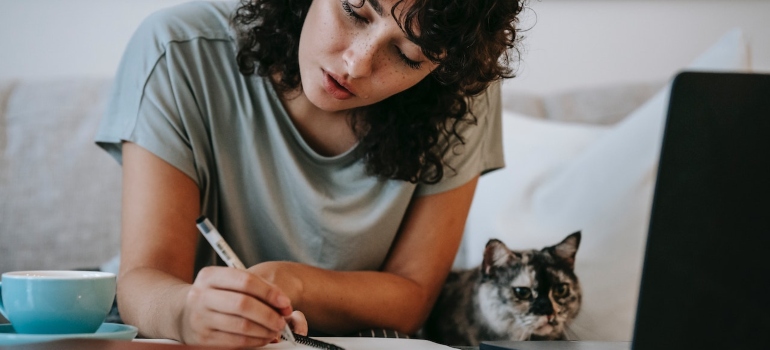 una mujer haciendo una lista de obligaciones después de hacer la investigación para planificar adecuadamente una cruz país mudarse a Houston